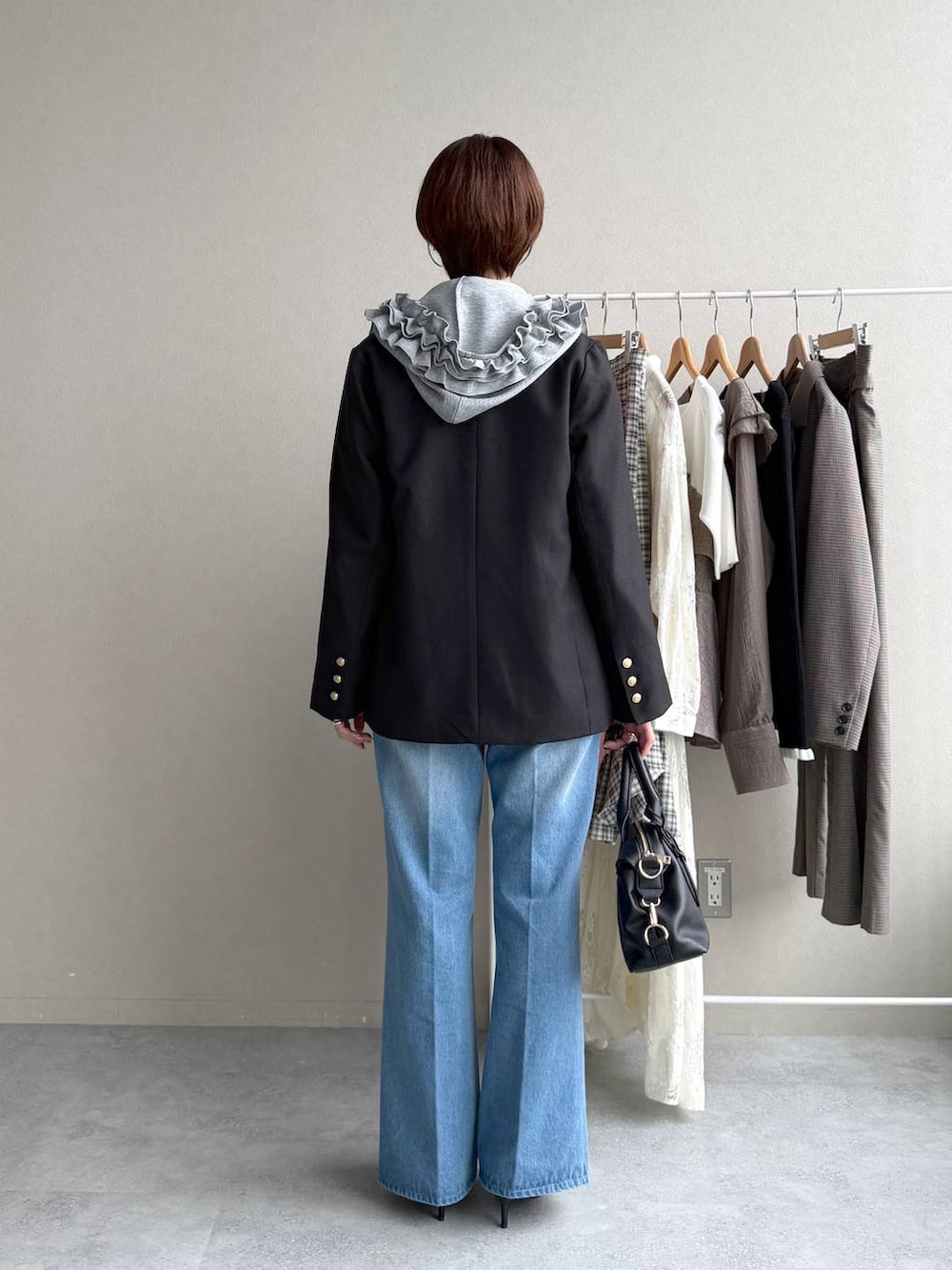 ブルー系のデニムパンツ、グレー系のパーカー、ブラック系のボストンバッグを着用したレディースの秋コーディネートの3枚目の写真