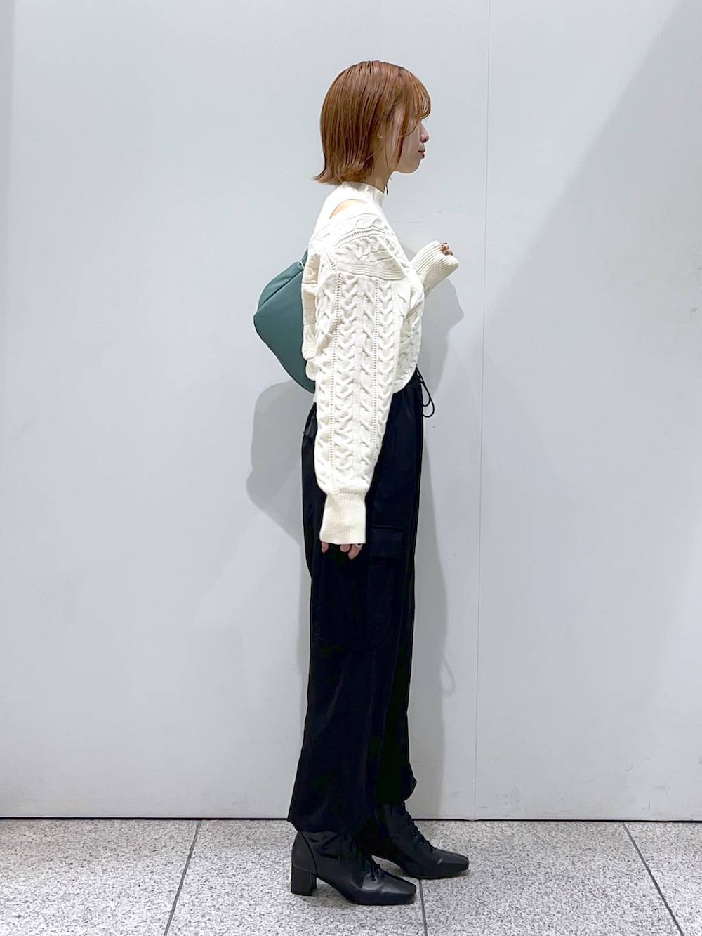 ブラック系のブーツ、グリーン系のハンドバッグ、ホワイト系のニット/セーターを着用したレディースの秋コーディネートの2枚目の写真