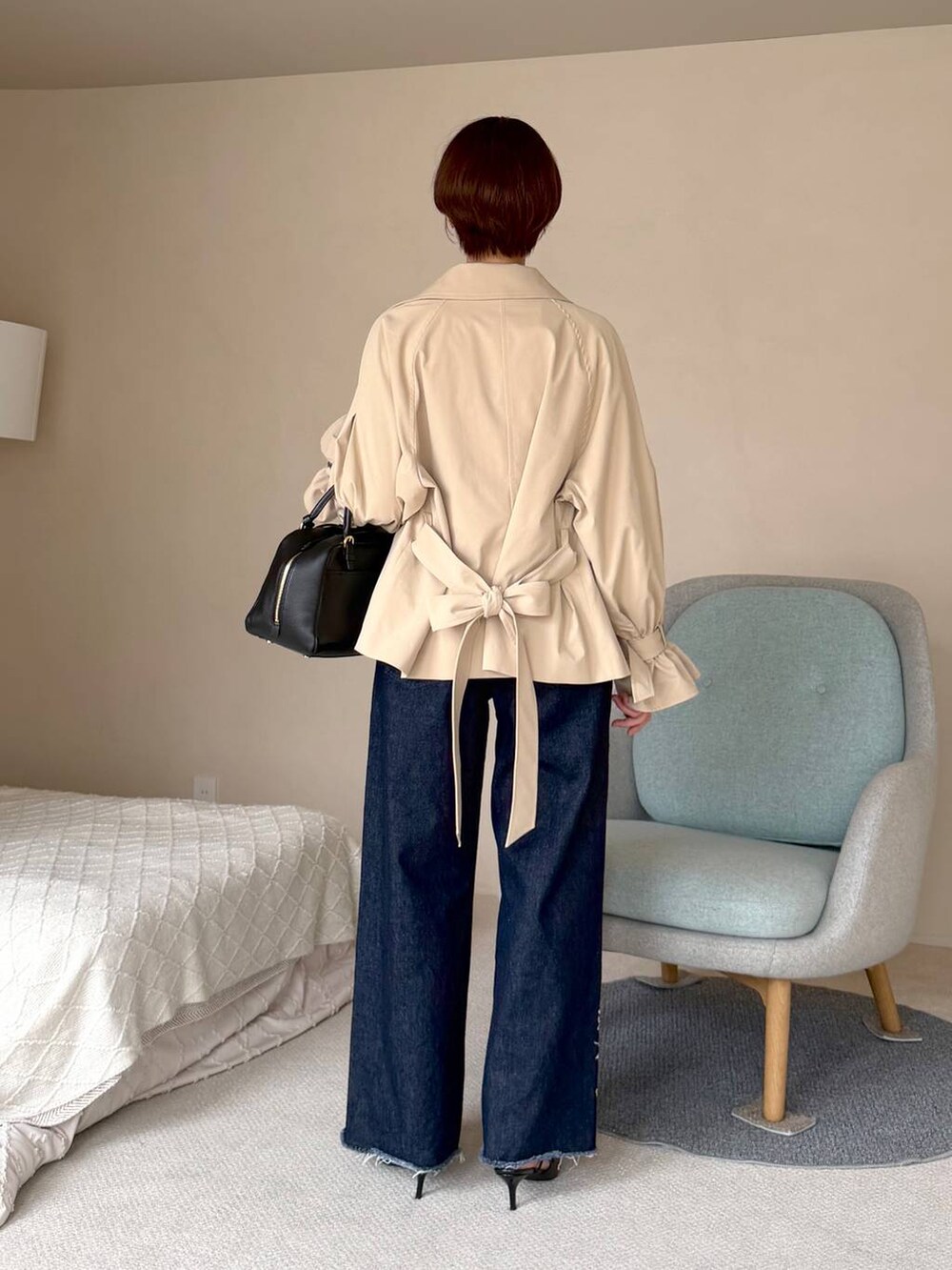 ブルー系のデニムパンツ、ベージュ系のトレンチコート、ブラック系のハンドバッグを着用したレディースの秋コーディネートの3枚目の写真