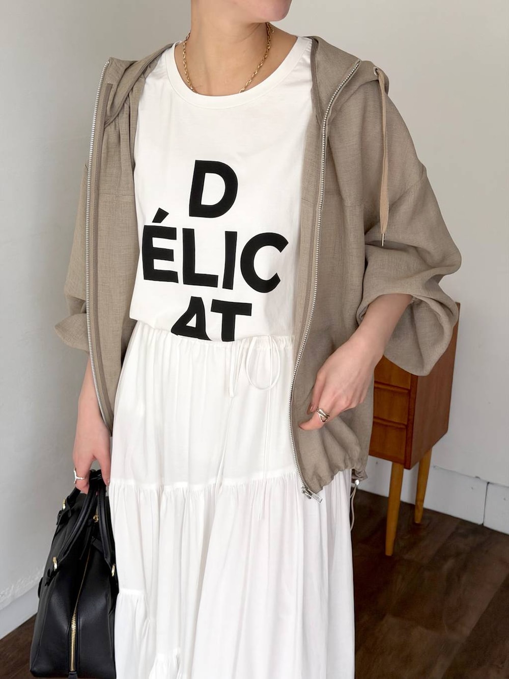 ブラック系のハンドバッグ、ブラック系のサンダル、ホワイト系のスカートを着用したレディースの春コーディネートの4枚目の写真