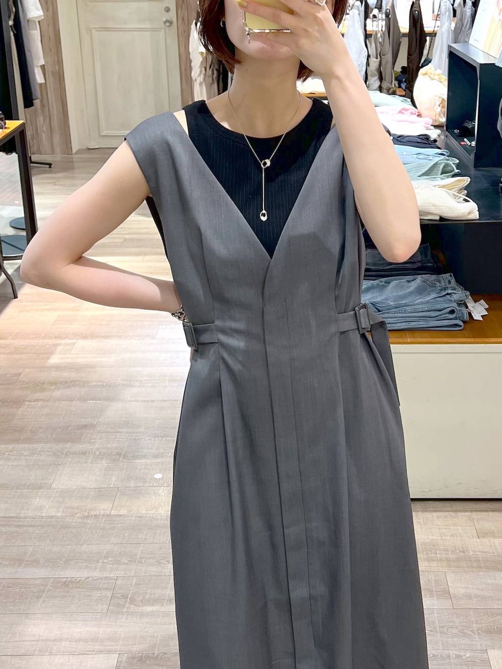 ブラック系のハンドバッグ、ブラック系のサンダル、グレー系のジャンパースカートを着用したレディースの夏コーディネートの4枚目の写真