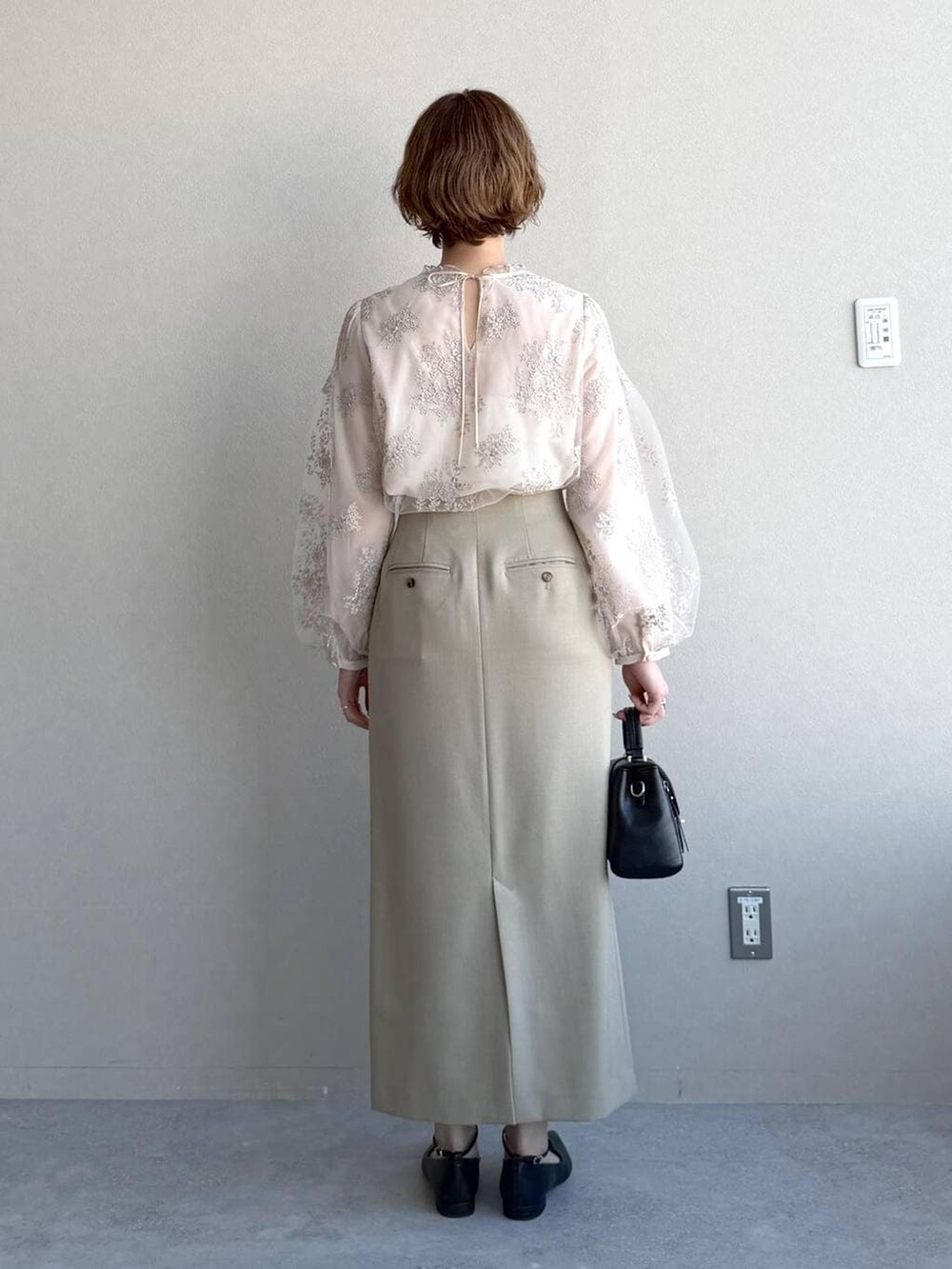 ブラック系のショルダーバッグ、ベージュ系のテーラードジャケット、ベージュ系のスカートを着用したレディースの冬コーディネートの6枚目の写真