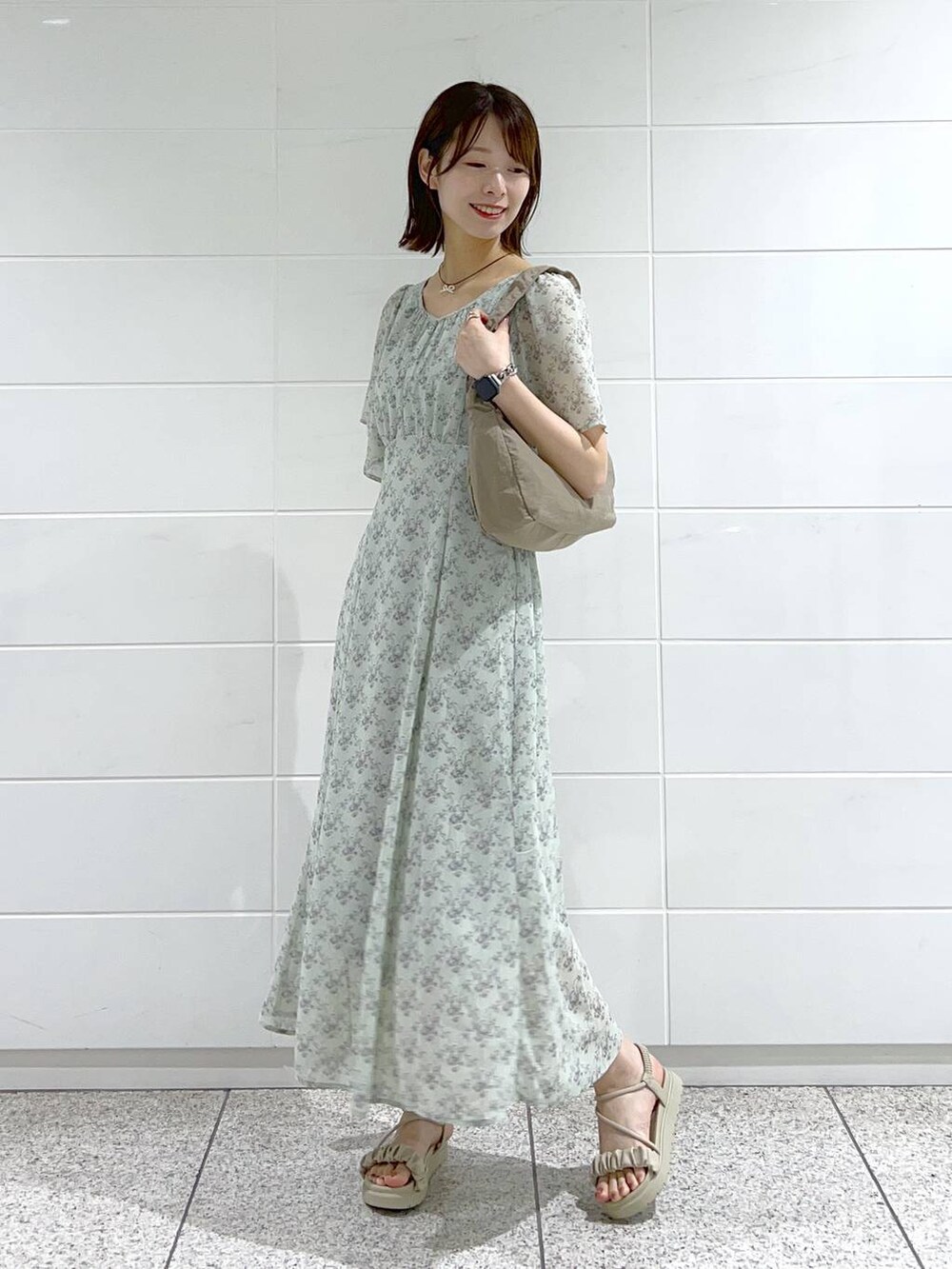 グレー系のサンダル、グリーン系のワンピース、ブラウン系のショルダーバッグを着用したレディースの春コーディネートの2枚目の写真