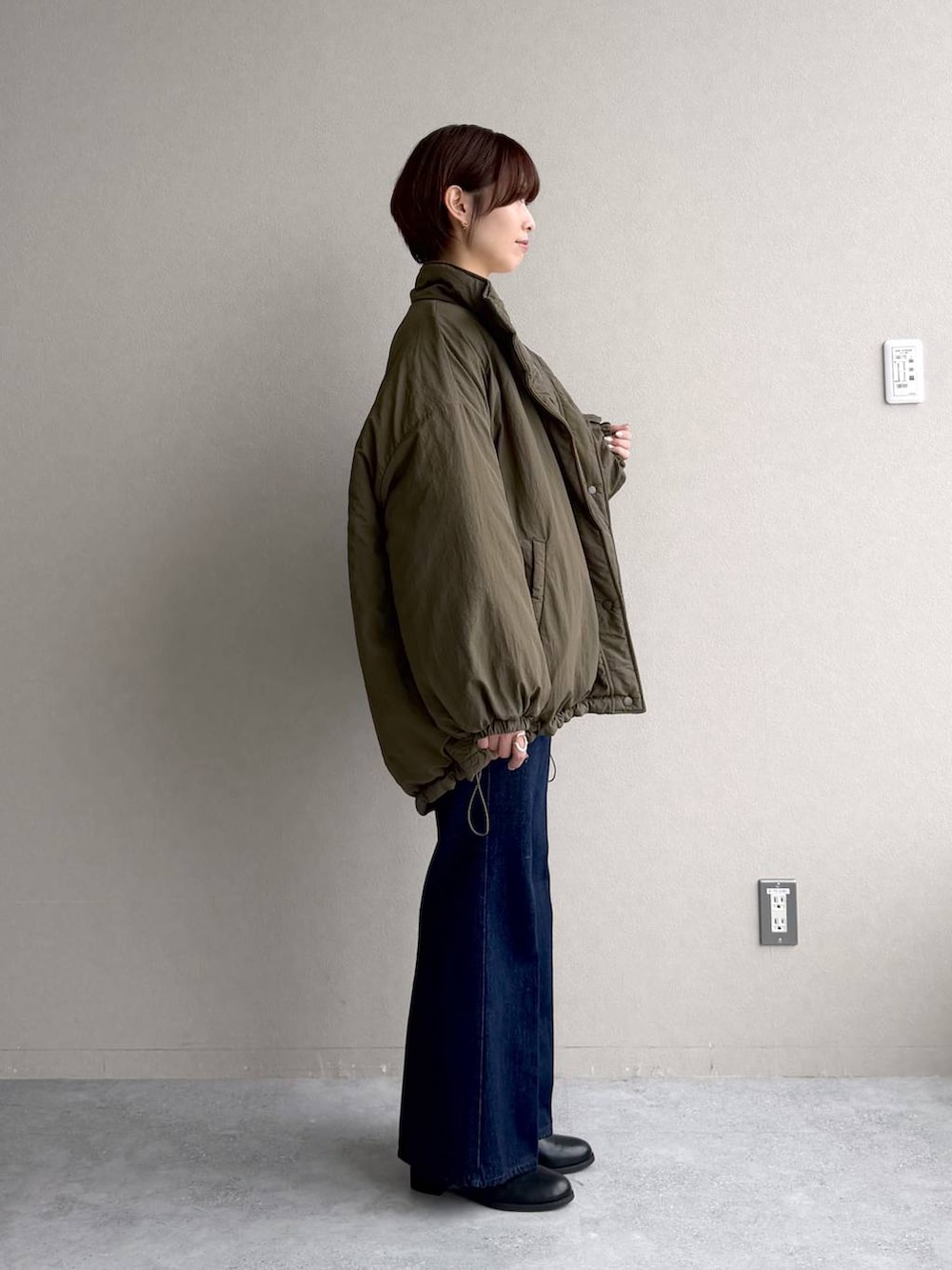 ブルー系のデニムパンツ、ホワイト系のカーディガン/ボレロ、ブラック系のボストンバッグを着用したレディースの秋コーディネートの2枚目の写真