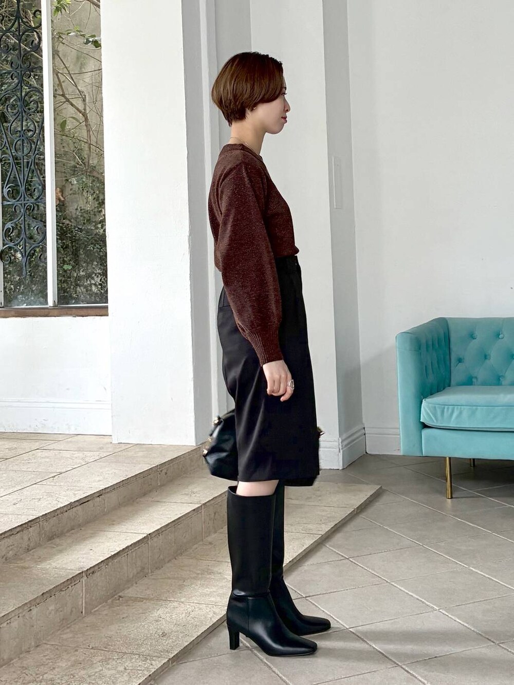 ブラウン系のニット/セーター、ブラック系のボストンバッグ、ブラック系のブーツを着用したレディースの冬コーディネートの5枚目の写真