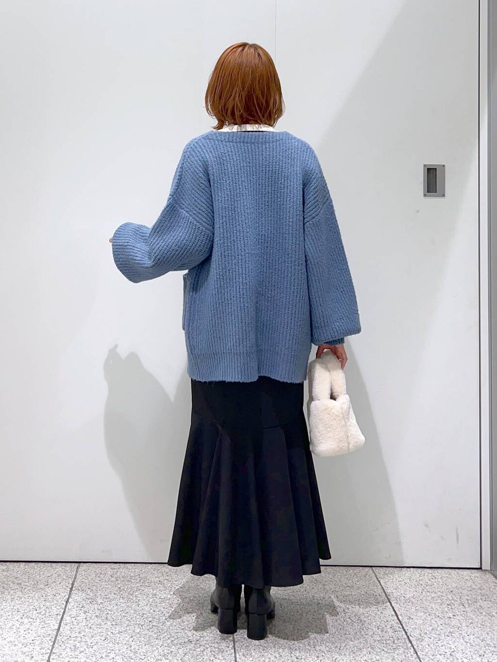 ブラック系のブーツ、ブラック系のスカート、ホワイト系のニット/セーターを着用したレディースの秋コーディネートの3枚目の写真