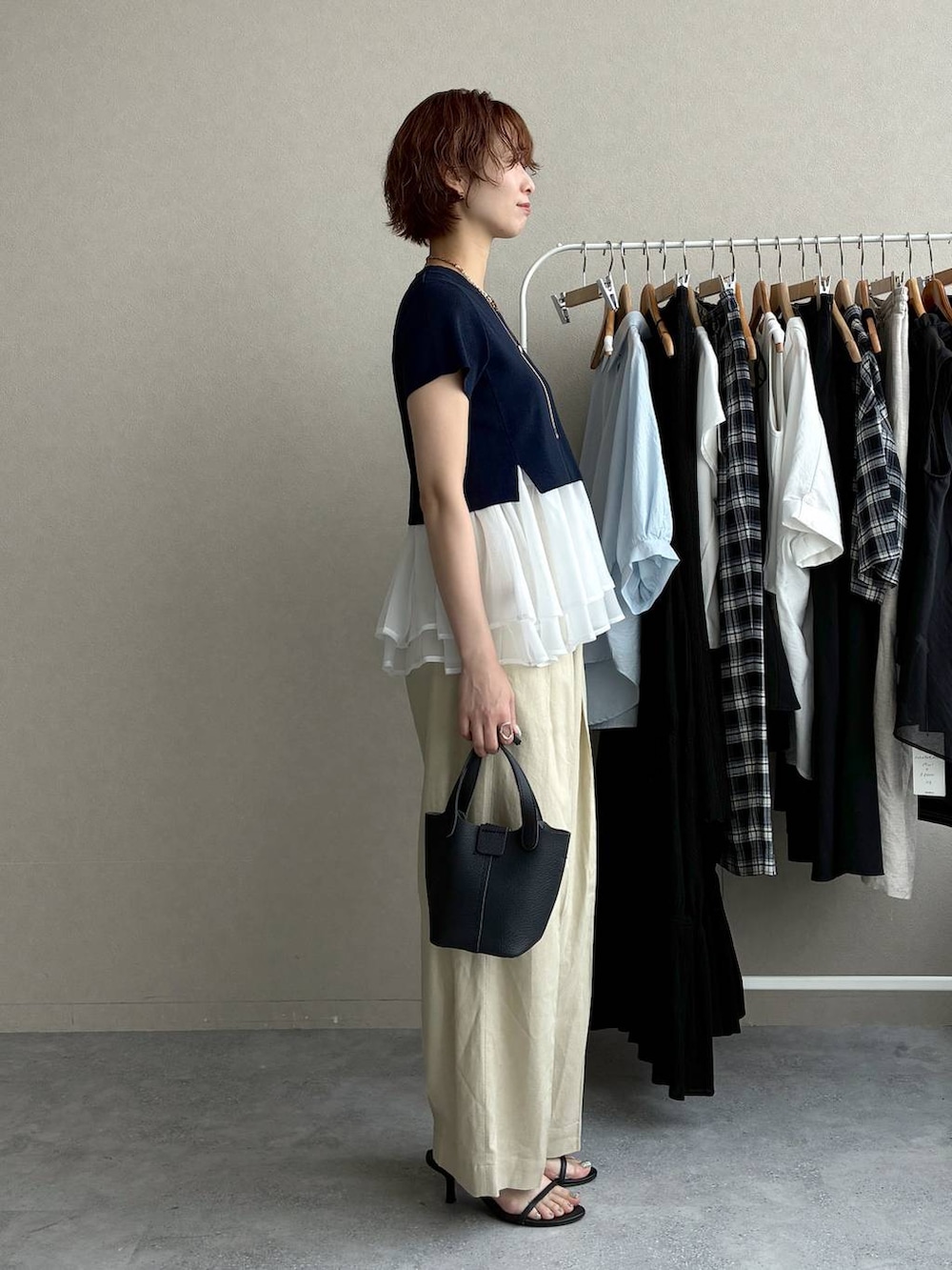 ブルー系のニット/セーター、ベージュ系のその他パンツ、ブラック系のショルダーバッグを着用したレディースの夏コーディネートの2枚目の写真