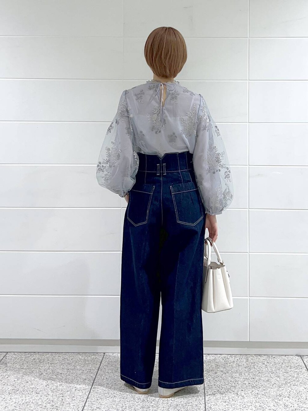 ホワイト系のショルダーバッグ、シルバー系のバレエシューズ、ブルー系のデニムパンツを着用したレディースの春コーディネートの3枚目の写真