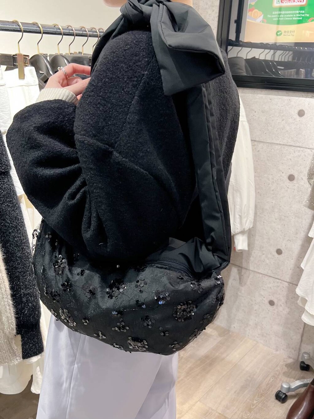 ブラック系のショルダーバッグ、ブラック系のブーツ、ホワイト系のニット/セーターを着用したレディースの冬コーディネートの5枚目の写真