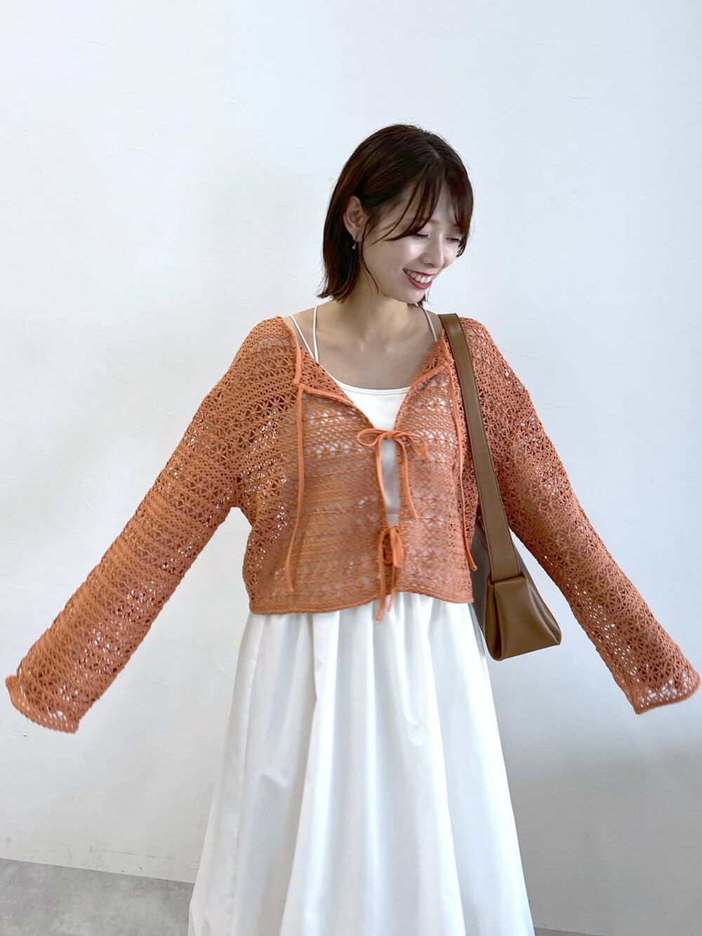 ホワイト系のサンダル、オレンジ系のカーディガン/ボレロ、ホワイト系のキャミソールを着用したレディースの春コーディネートの4枚目の写真