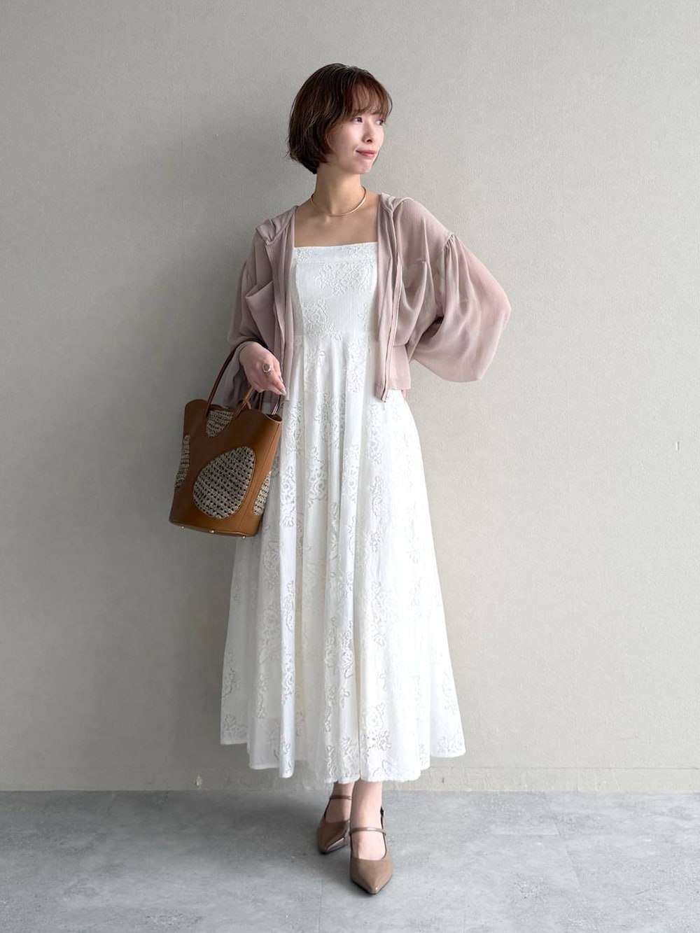 ベージュ系のパーカー、ブラウン系のトートバッグ、ホワイト系のワンピースを着用したレディースの春コーディネートの4枚目の写真