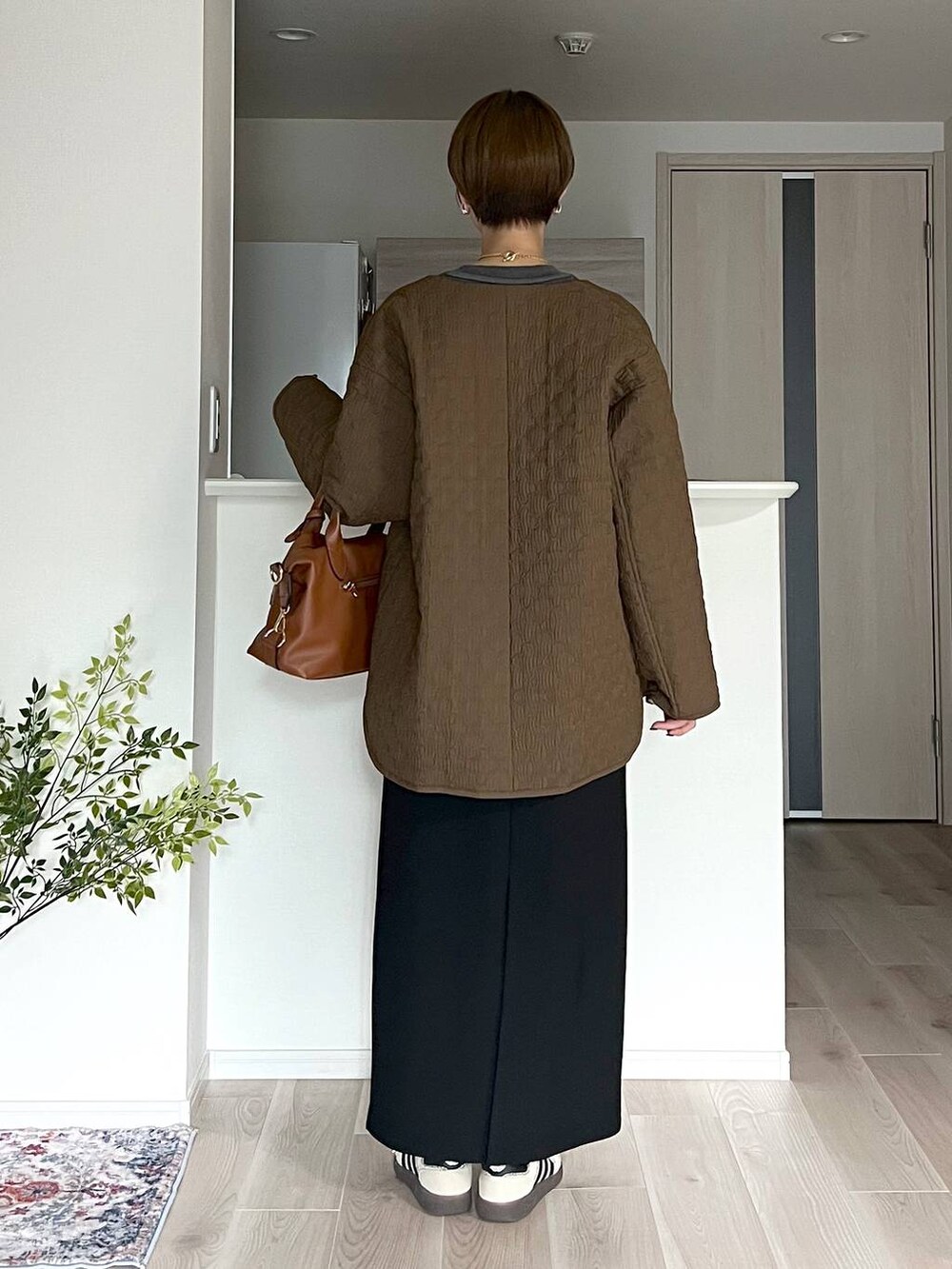 ブラウン系のボストンバッグ、ブラック系のスカート、ベージュ系のネックレスを着用したレディースの秋コーディネートの3枚目の写真