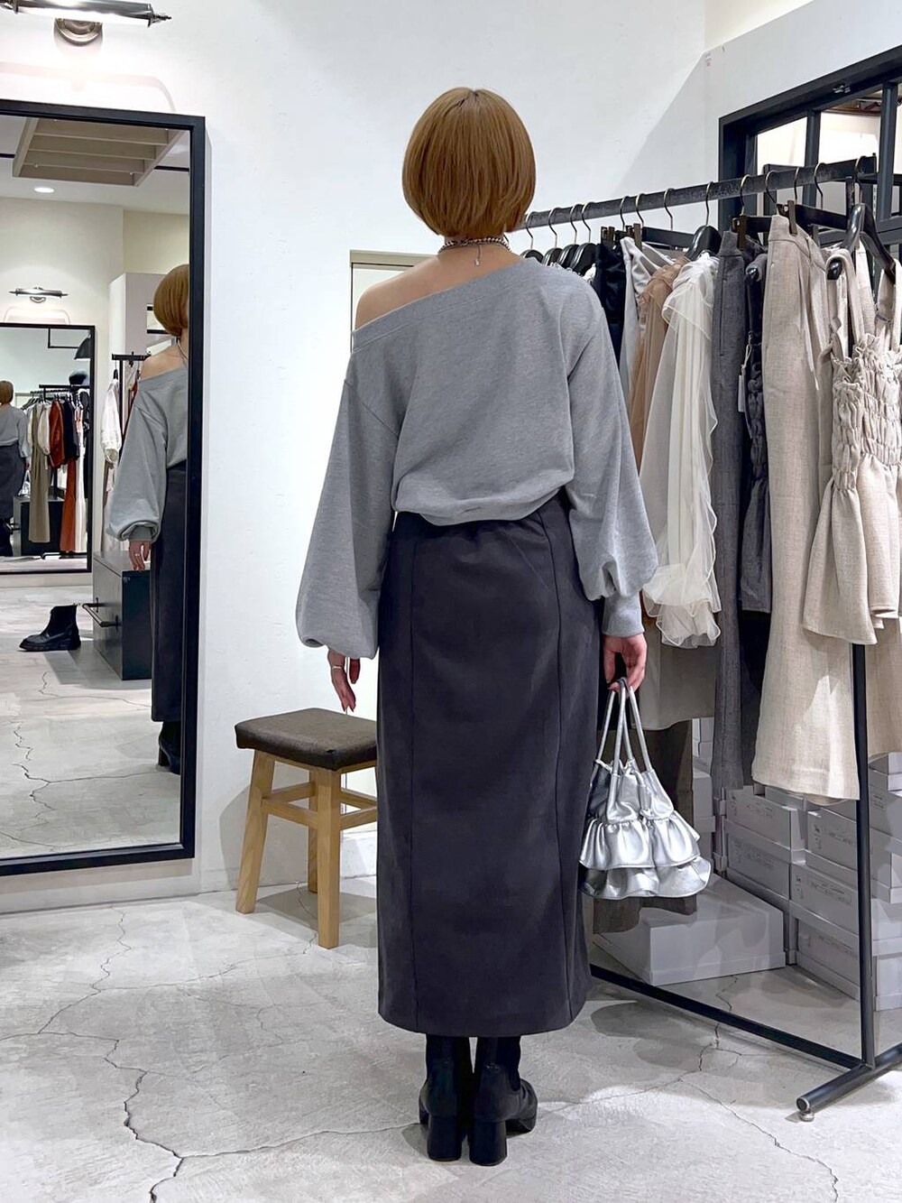 シルバー系のショルダーバッグ、ブラック系のブーツ、グレー系のスカートを着用したレディースの秋コーディネートの3枚目の写真