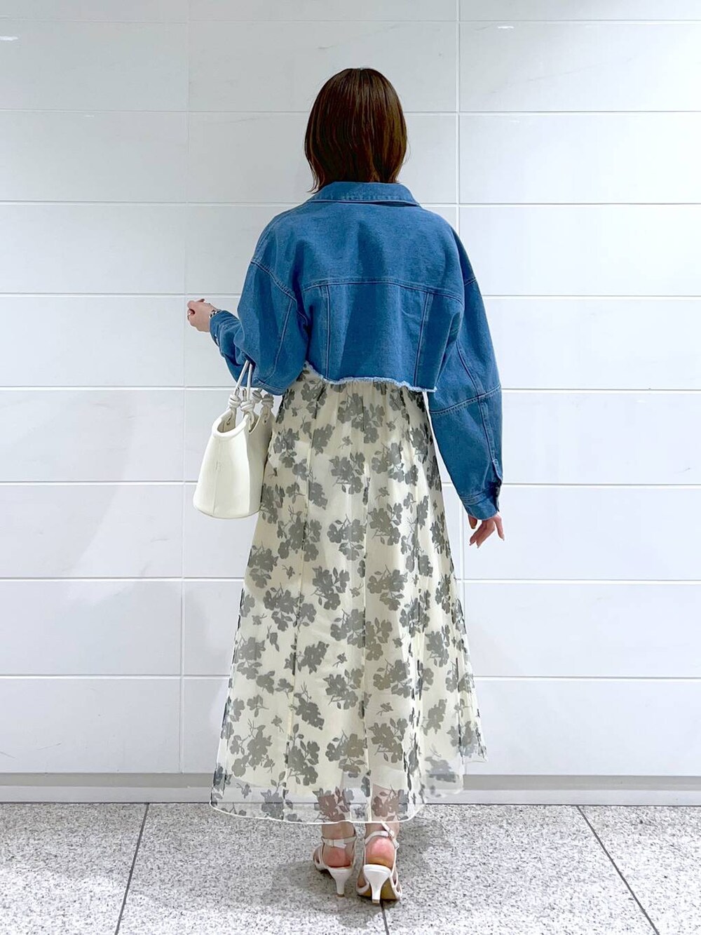 ホワイト系のハンドバッグ、ホワイト系のワンピース、ブルー系のデニムジャケットを着用したレディースの春コーディネートの4枚目の写真