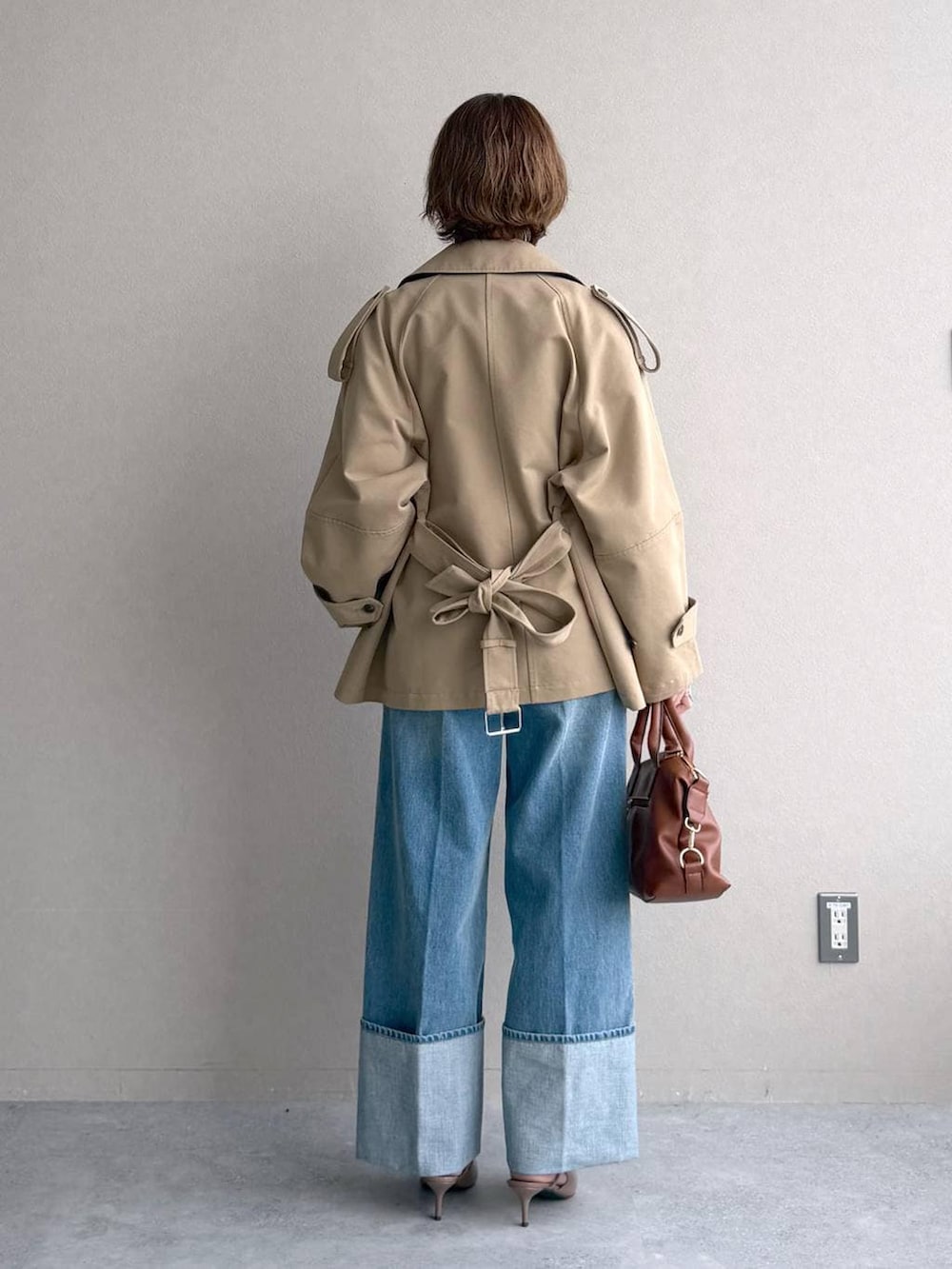 イエロー系のニット/セーター、ブラウン系のボストンバッグ、ベージュ系のトレンチコートを着用したレディースの冬コーディネートの3枚目の写真