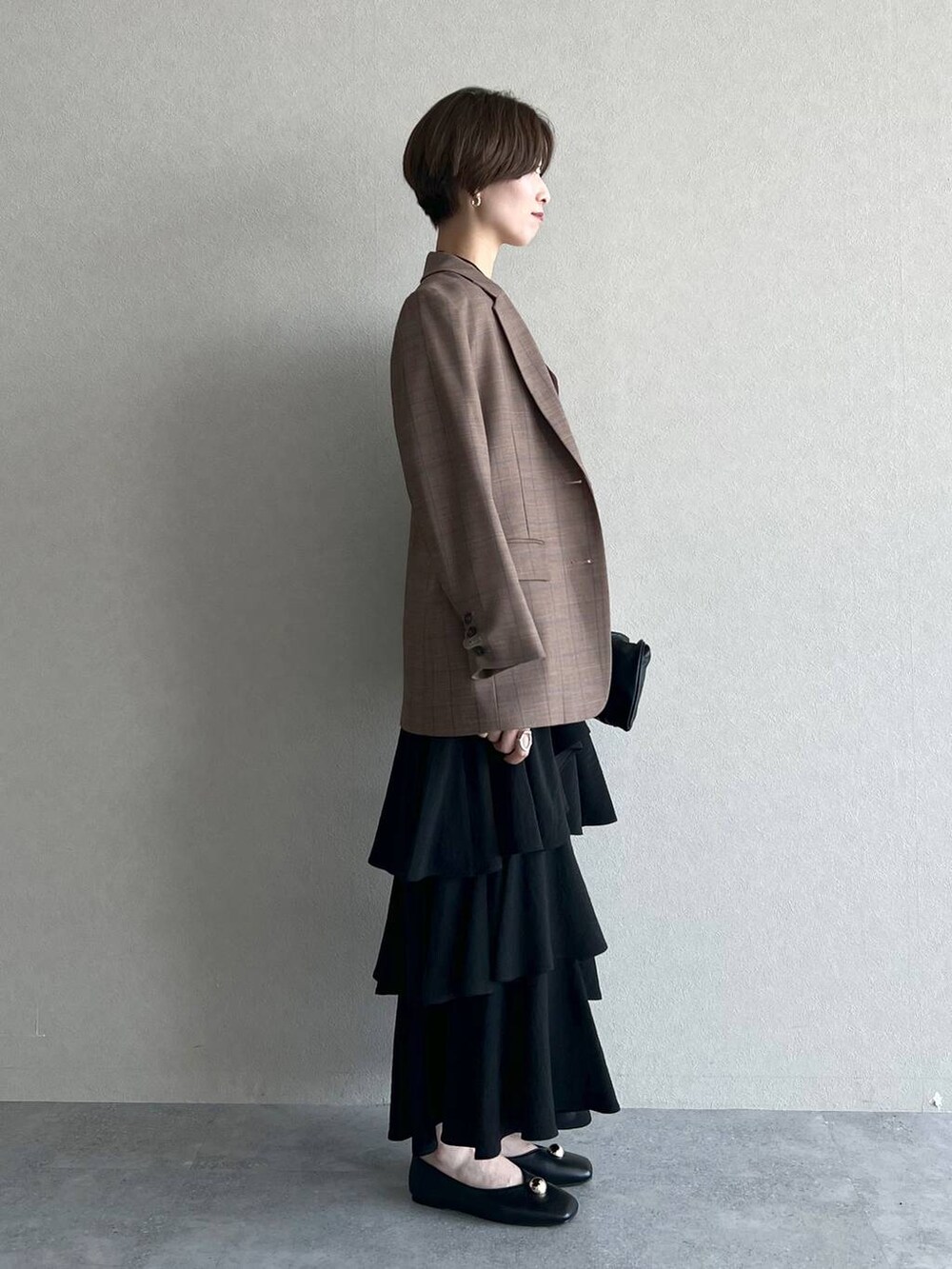 ブラック系のハンドバッグ、ベージュ系のテーラードジャケット、ブラック系のスカートを着用したレディースの秋コーディネートの2枚目の写真