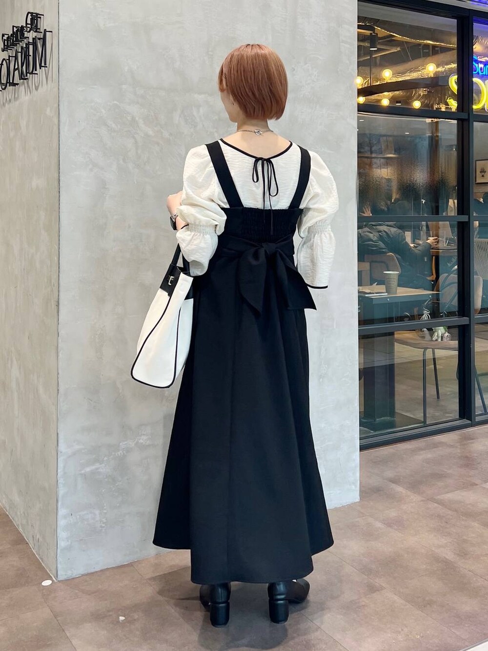 ブラック系のトートバッグ、ホワイト系のシャツ/ブラウス、ブラック系のパンプスを着用したレディースの春コーディネートの2枚目の写真