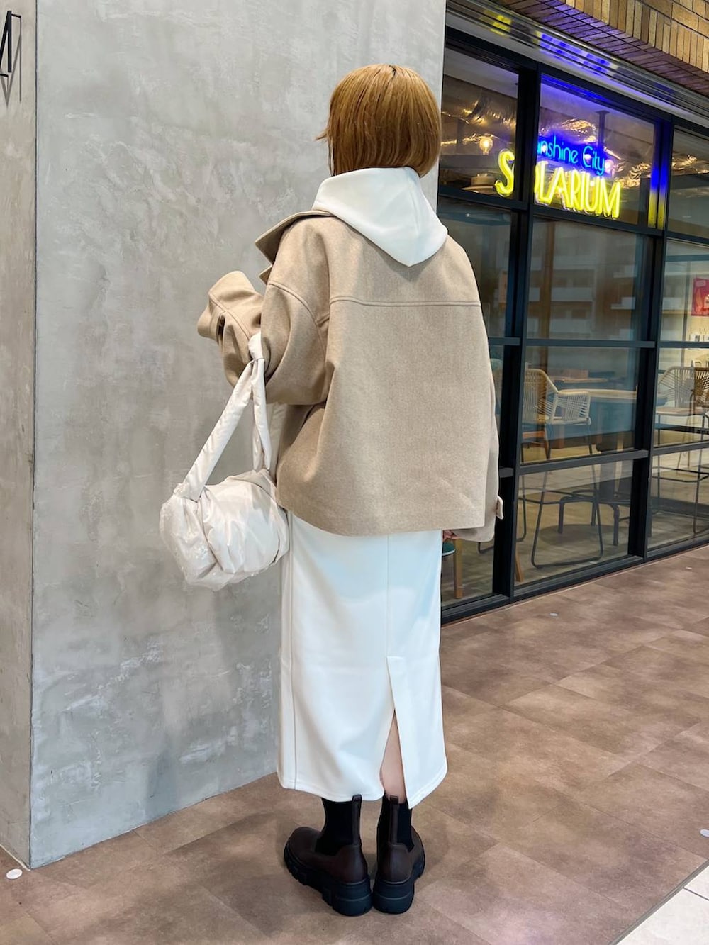 ベージュ系のピーコート、ホワイト系のショルダーバッグ、ブラウン系のブーツを着用したレディースの秋コーディネートの3枚目の写真