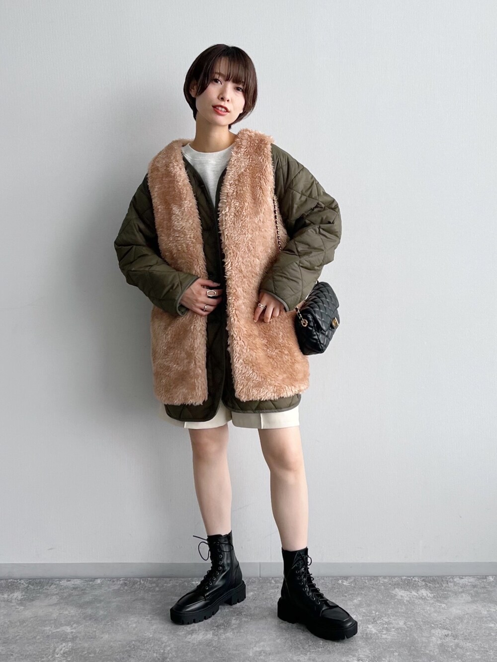 グリーン系のブルゾン、ブラック系のブーツ、ホワイト系のその他パンツを着用したレディースの夏コーディネートの2枚目の写真