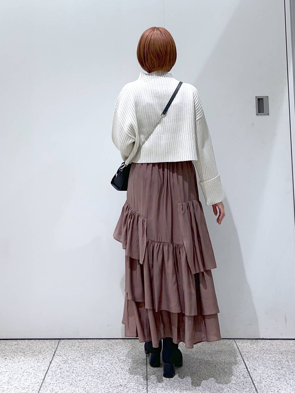 ブラック系のボストンバッグ、ブラック系のブーツ、ブラウン系のスカートを着用したレディースの冬コーディネートの3枚目の写真