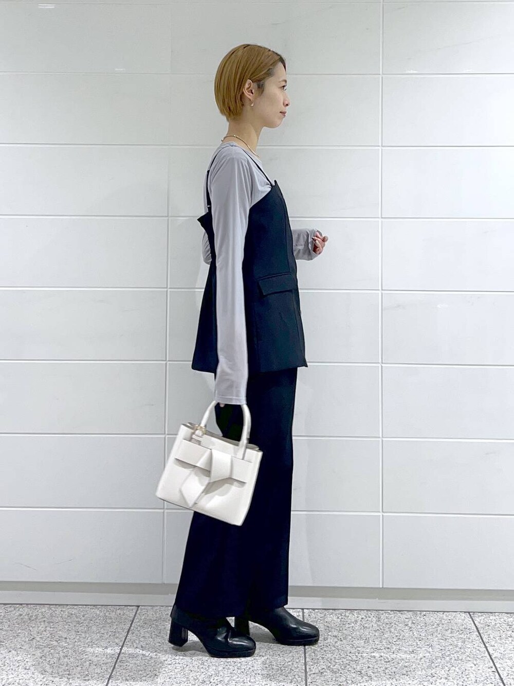 グレー系のTシャツ/カットソー、ブラック系のブーツ、ホワイト系のショルダーバッグを着用したレディースの冬コーディネートの5枚目の写真