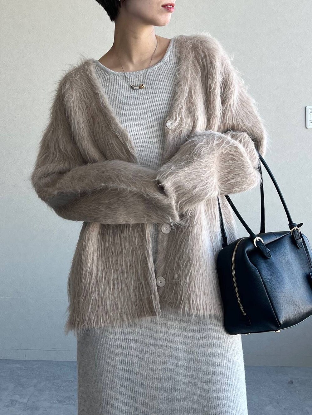 ブラック系のハンドバッグ、ブラック系のブーツ、ベージュ系のカーディガン/ボレロを着用したレディースの冬コーディネートの4枚目の写真