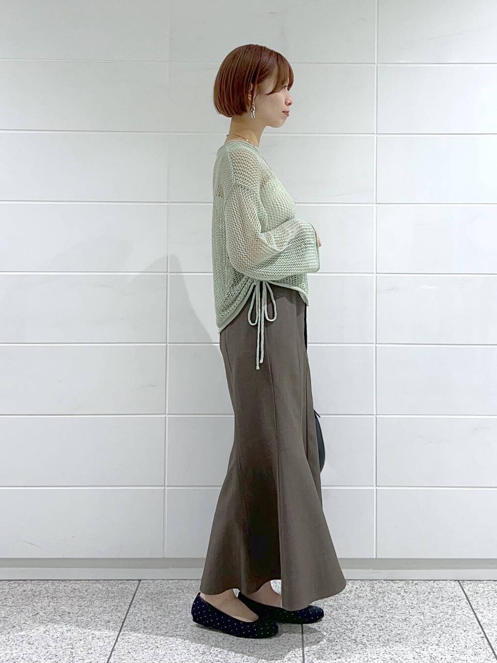 ブラック系のバレエシューズ、グリーン系のニット/セーター、グレー系のスカートを着用したレディースの春コーディネートの3枚目の写真