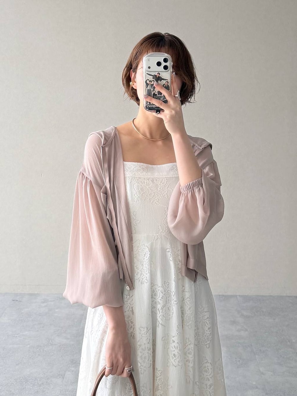 ベージュ系のパーカー、ブラウン系のトートバッグ、ホワイト系のワンピースを着用したレディースの春コーディネートの6枚目の写真