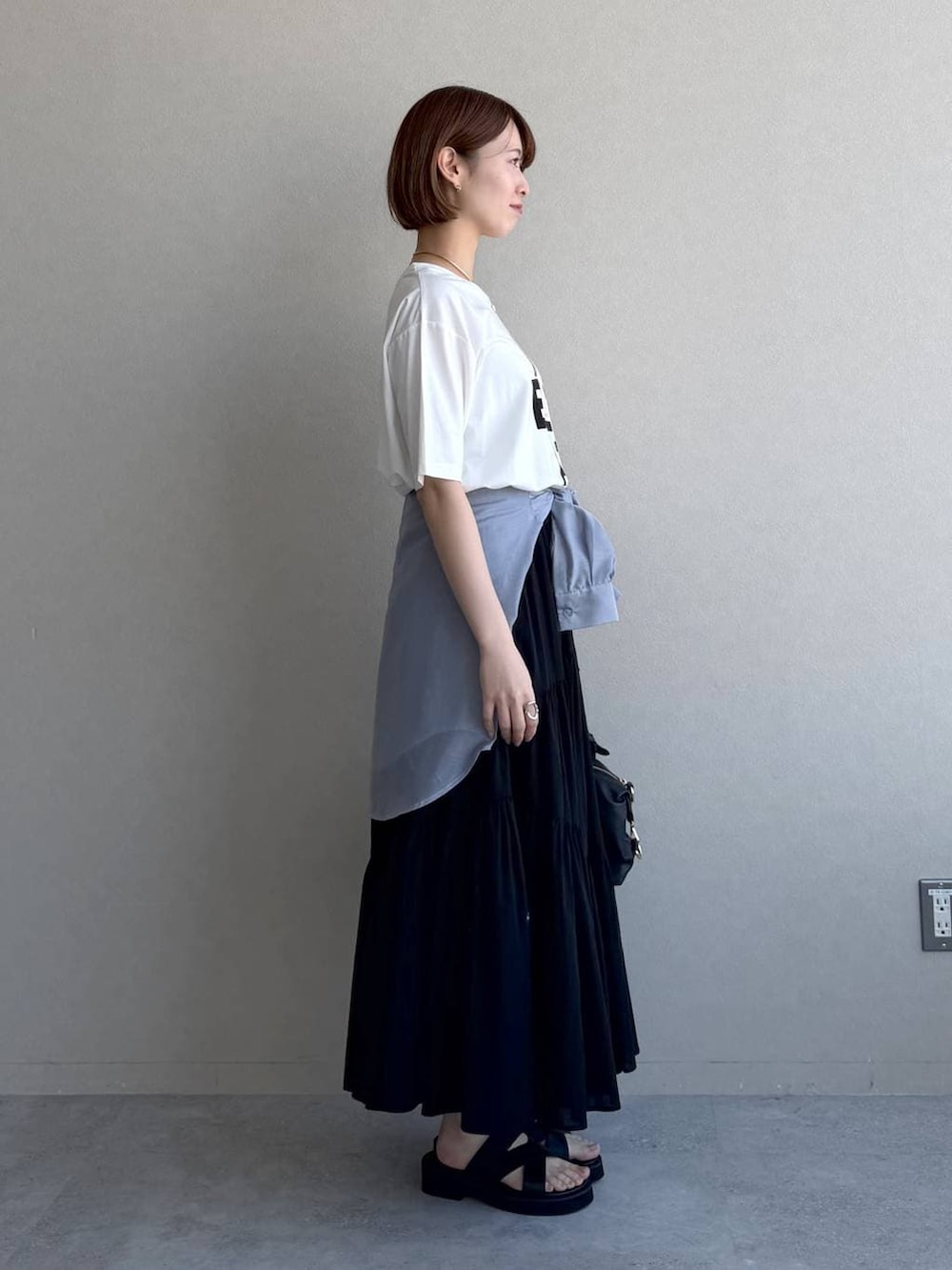 ブラック系のボストンバッグ、ブルー系のシャツ/ブラウス、ブラック系のサンダルを着用したレディースの春コーディネートの2枚目の写真