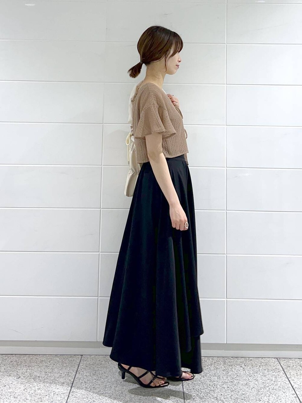 ホワイト系のショルダーバッグ、ブラウン系のカーディガン/ボレロ、ブラック系のサンダルを着用したレディースの夏コーディネートの2枚目の写真