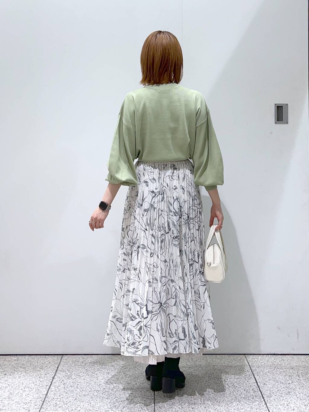 ホワイト系のブルゾン、ホワイト系のボストンバッグ、ブラック系のブーツを着用したレディースの秋コーディネートの6枚目の写真