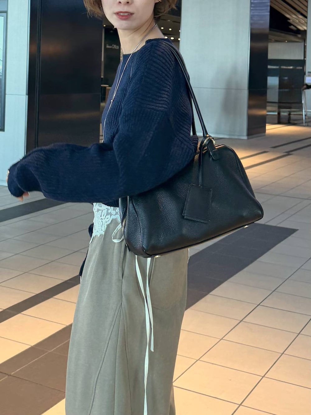 ブラック系のハンドバッグ、ブラック系のローファー、ブルー系のニット/セーターを着用したレディースの冬コーディネートの5枚目の写真