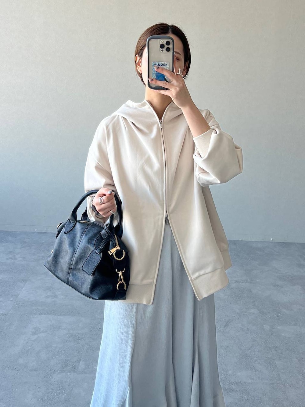 ブラック系のボストンバッグ、ブラック系のブーツ、ホワイト系のパーカーを着用したレディースの冬コーディネートの4枚目の写真