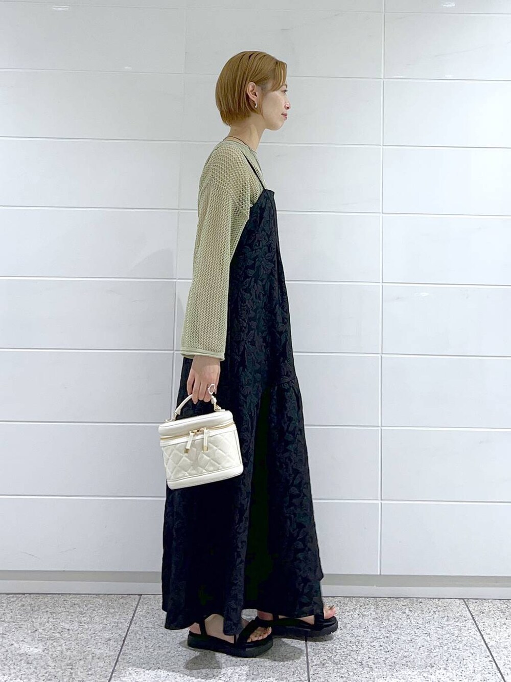 ブラック系のサンダル、ブラック系のワンピース、ホワイト系のショルダーバッグを着用したレディースの夏コーディネートの2枚目の写真