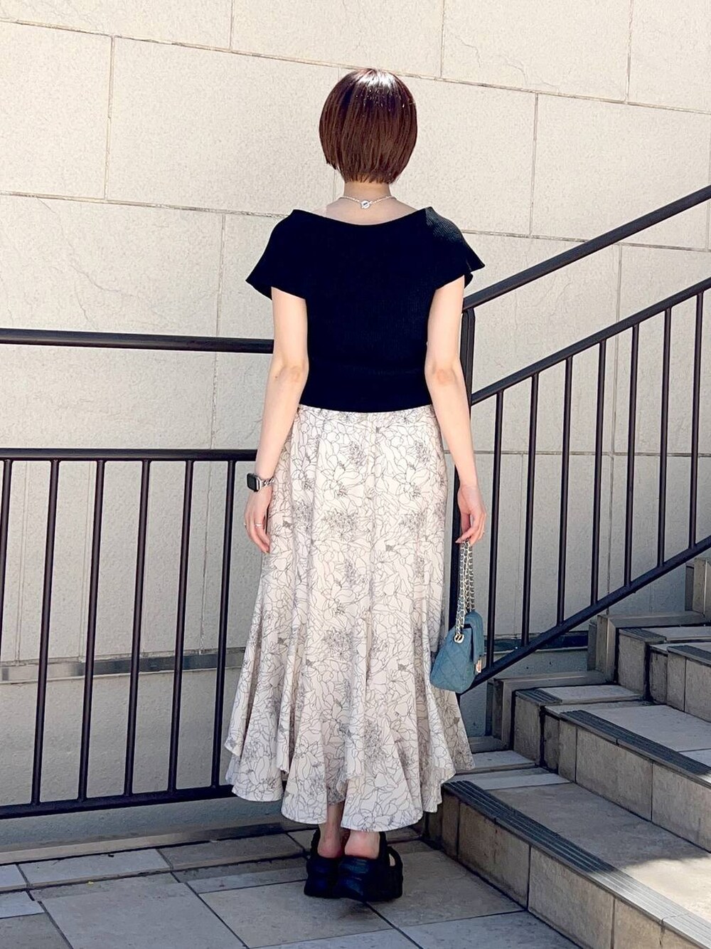 ブラック系のニット/セーター、ブルー系のショルダーバッグ、ホワイト系のスカートを着用したレディースの夏コーディネートの4枚目の写真