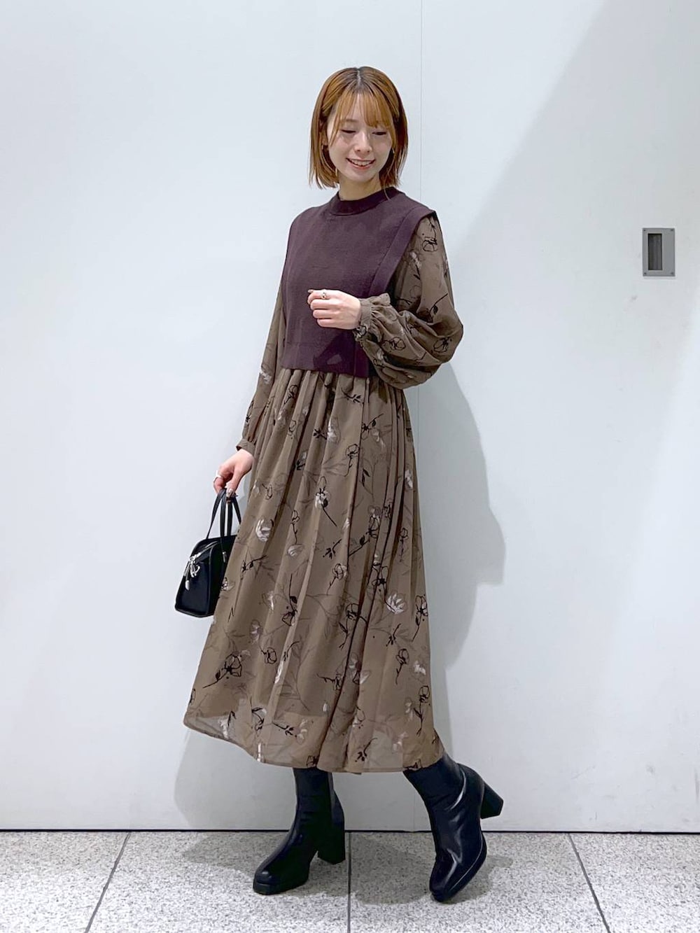 ホワイト系のチェスターコート、ブラック系のボストンバッグ、ブラック系のブーツを着用したレディースの秋コーディネートの4枚目の写真