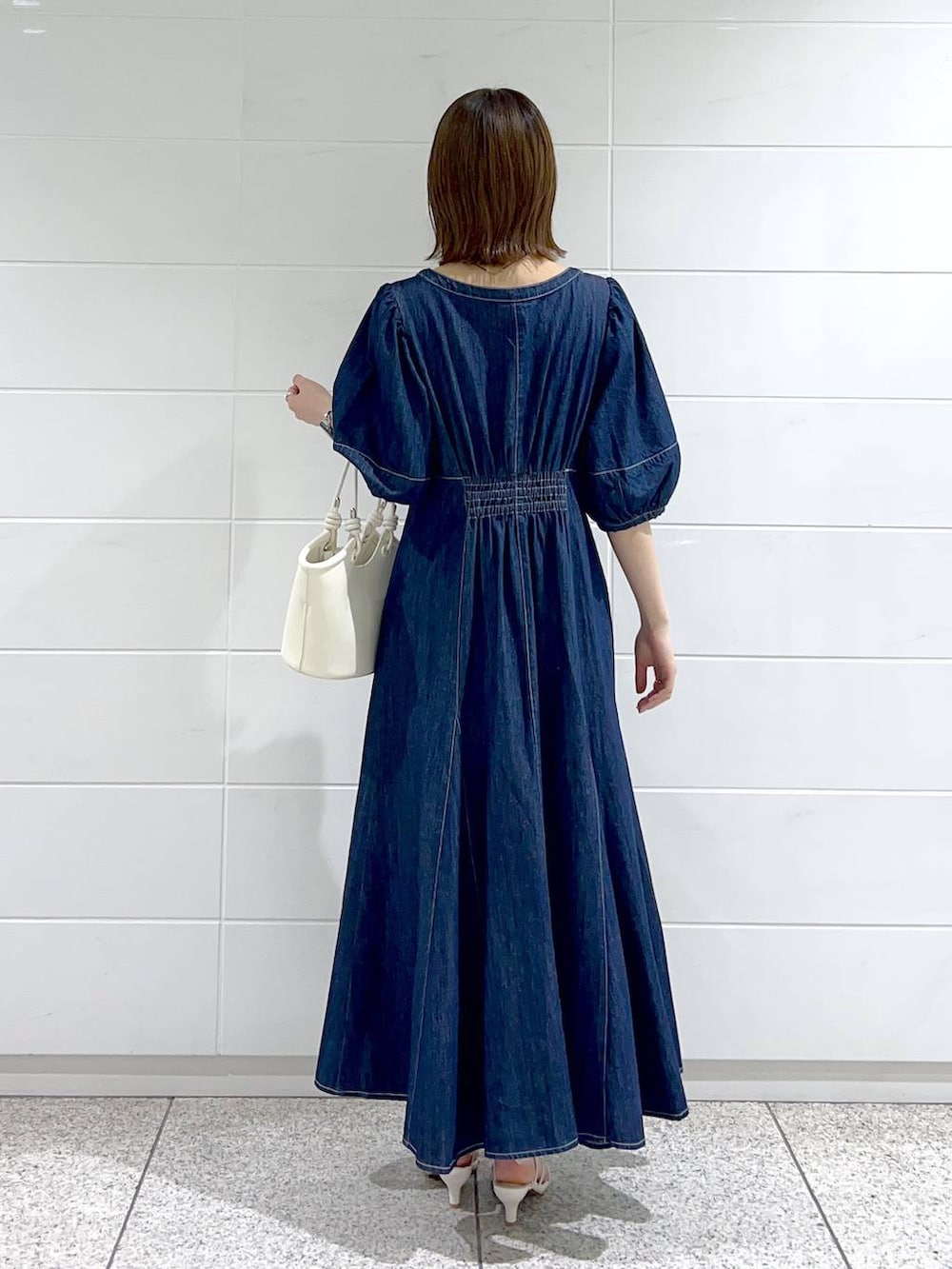 ブルー系のワンピース、ホワイト系のサンダル、ホワイト系のハンドバッグを着用したレディースの春コーディネートの4枚目の写真