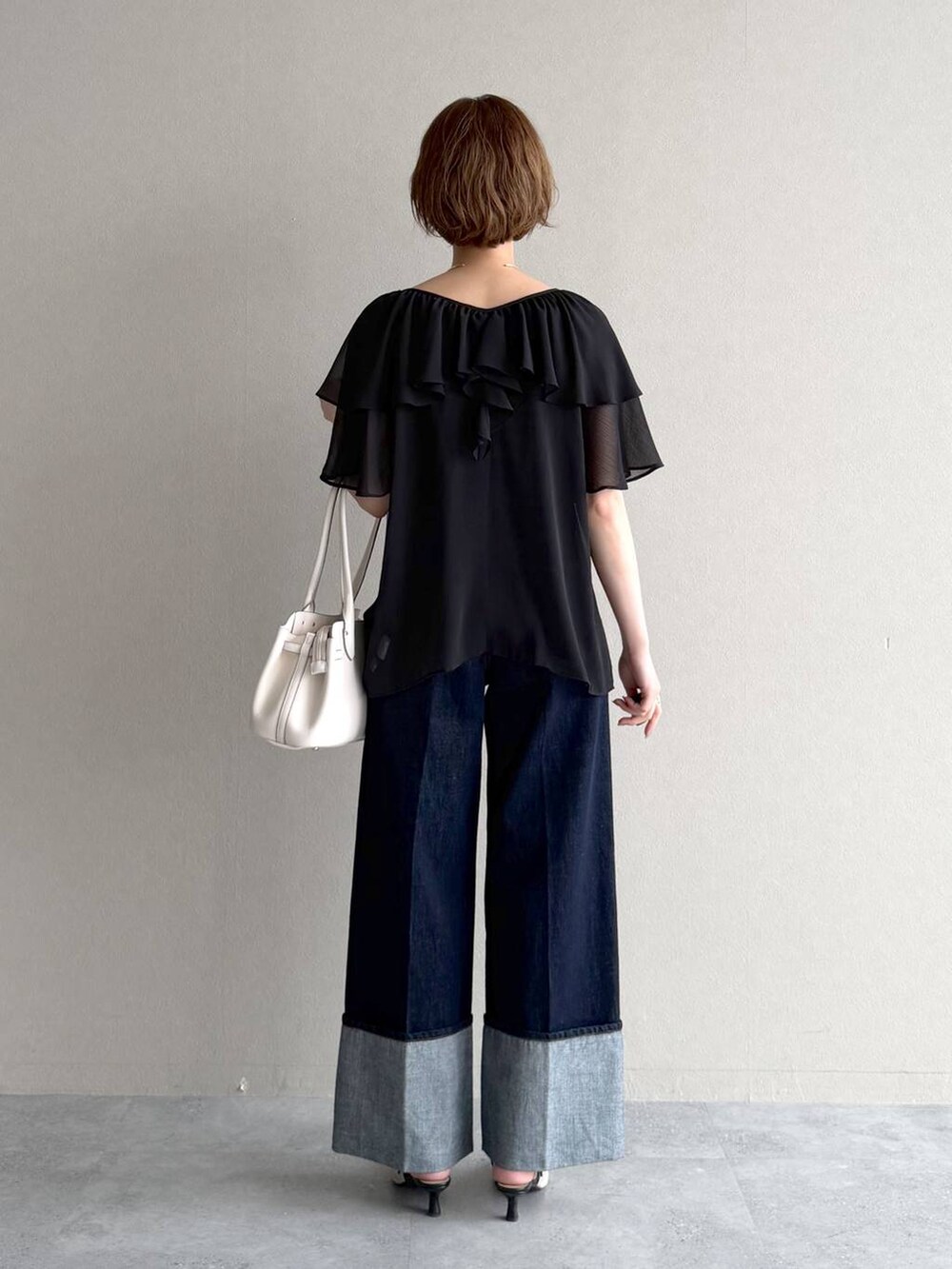 ホワイト系のサンダル、ブルー系のデニムパンツ、ブラック系のシャツ/ブラウスを着用したレディースの春コーディネートの3枚目の写真