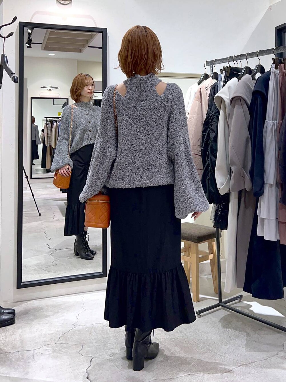 ブラック系のブーツ、オレンジ系のショルダーバッグ、ブラック系のスカートを着用したレディースの秋コーディネートの3枚目の写真