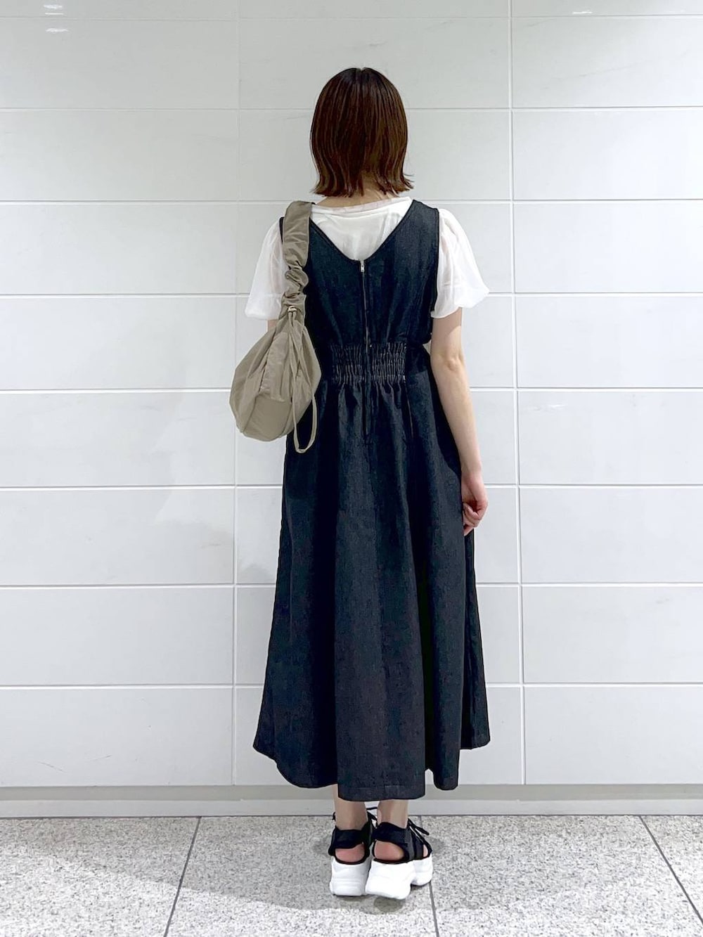 ブラック系のサンダル、ブラック系のジャンパースカート、ブラウン系のショルダーバッグを着用したレディースの春コーディネートの4枚目の写真