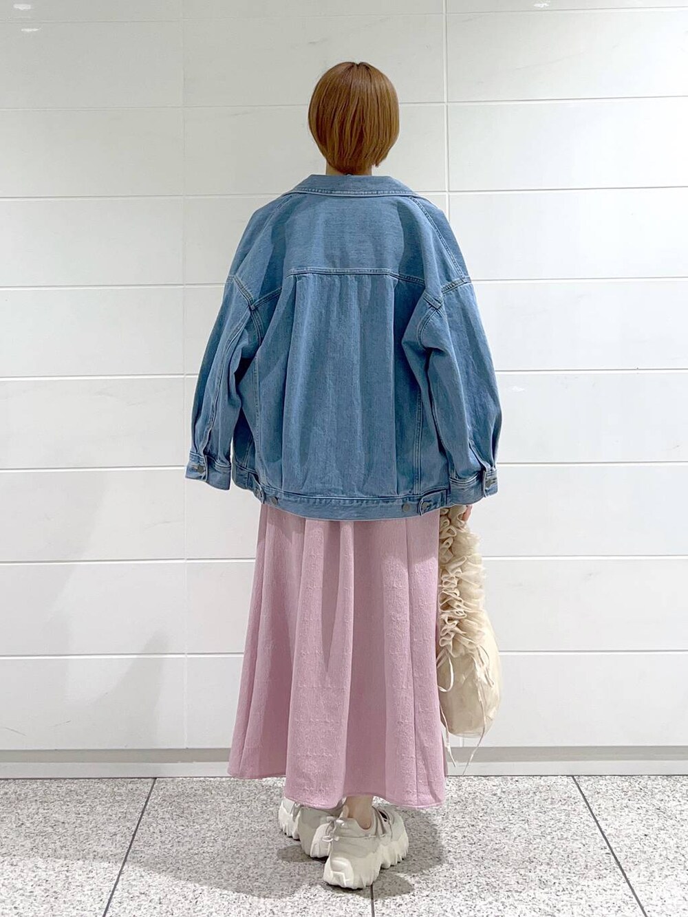 ベージュ系のショルダーバッグ、ブルー系のデニムジャケット、ホワイト系のバレエシューズを着用したレディースの春コーディネートの3枚目の写真