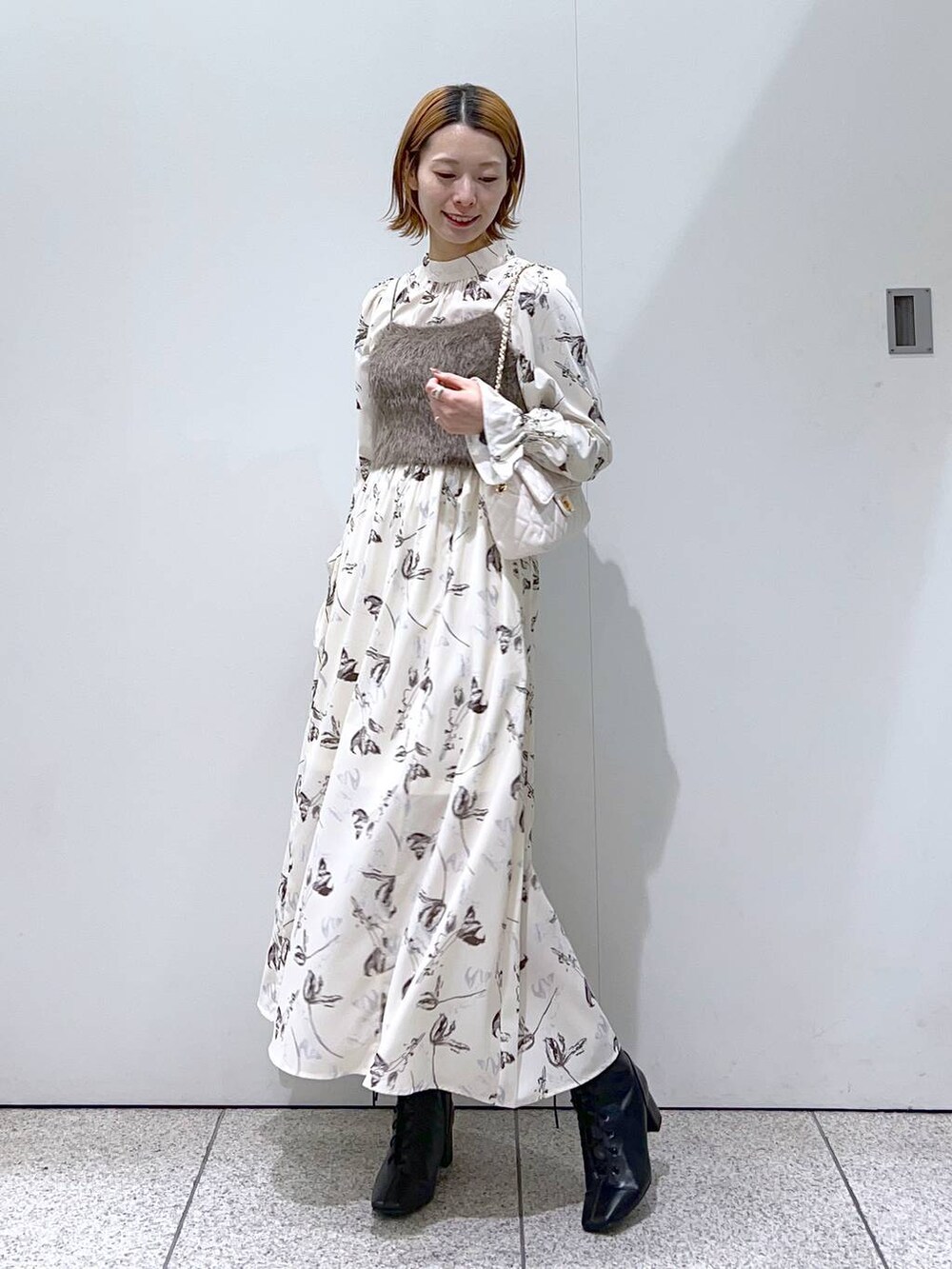 ホワイト系のショルダーバッグ、ブラック系のブーツ、ホワイト系のチェスターコートを着用したレディースの冬コーディネートの4枚目の写真