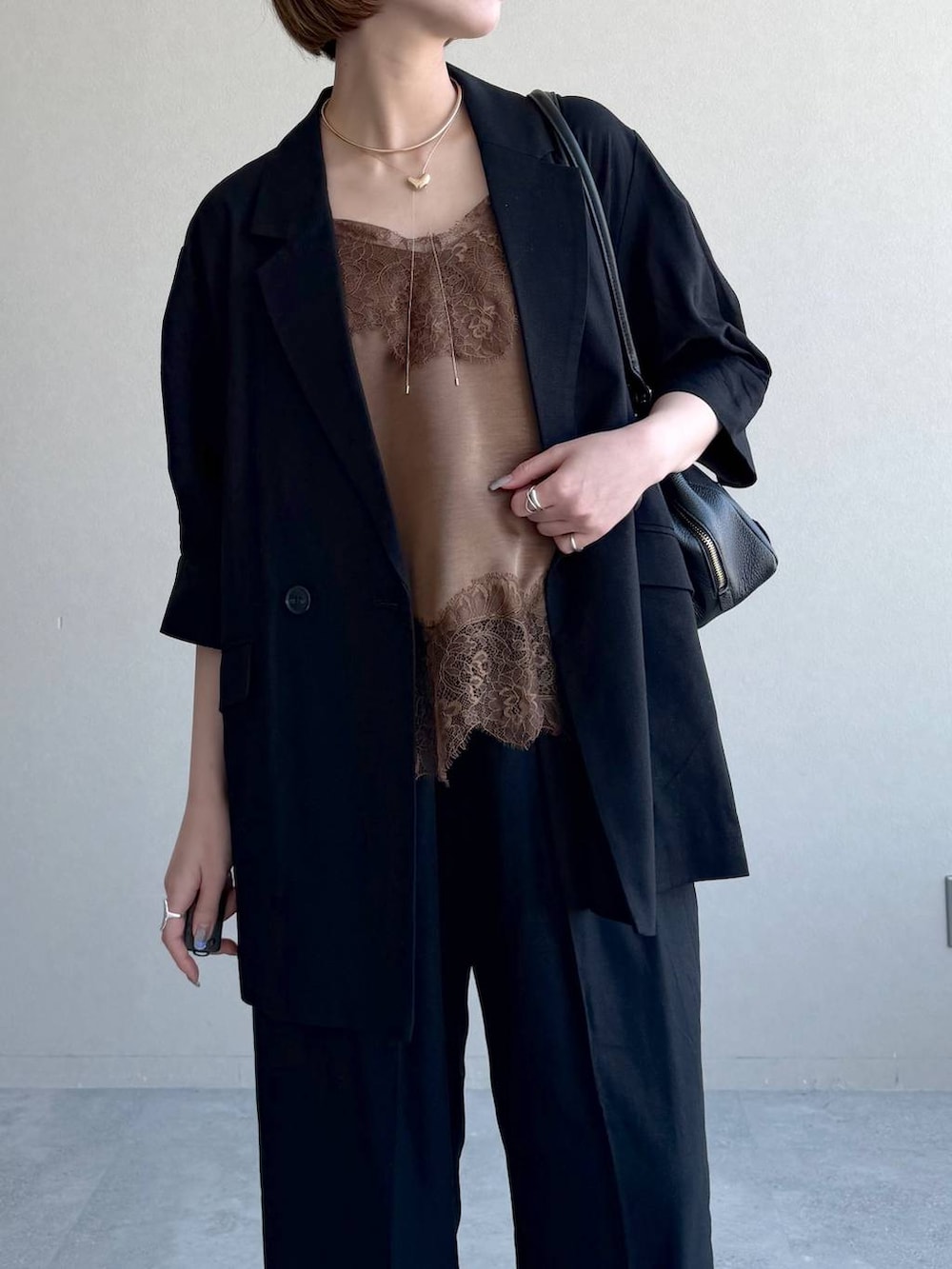 ブラック系のハンドバッグ、ブラック系のサンダル、ブラウン系のキャミソールを着用したレディースの春コーディネートの4枚目の写真