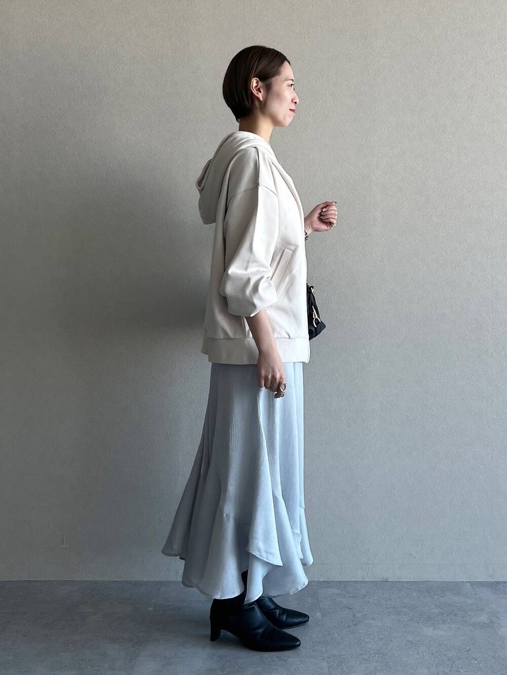 ブラック系のボストンバッグ、ブラック系のブーツ、ホワイト系のパーカーを着用したレディースの冬コーディネートの2枚目の写真