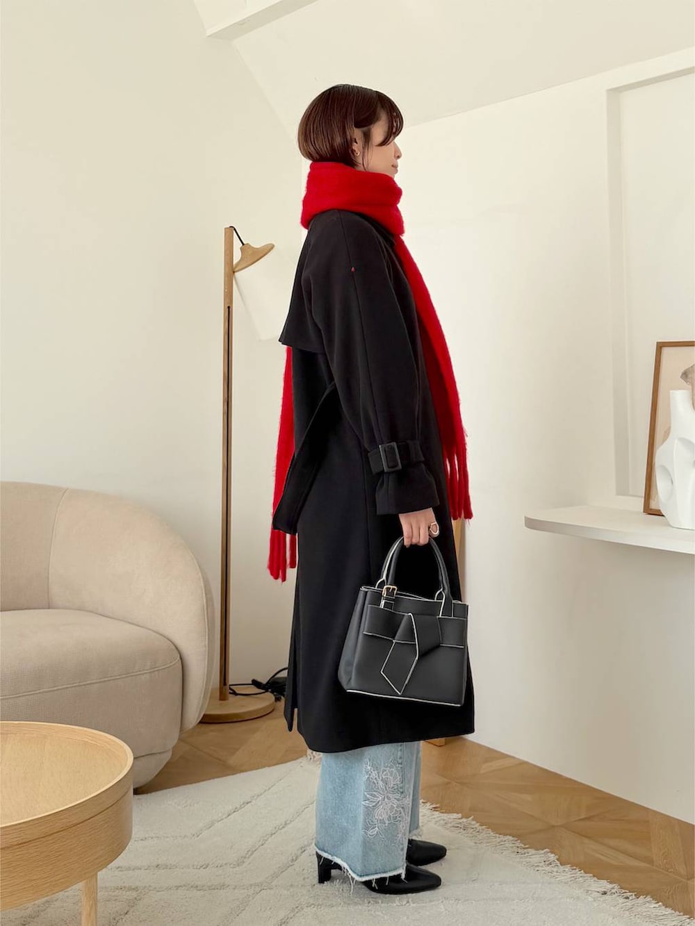 ブルー系のデニムパンツ、ブラック系のショルダーバッグ、ブラック系のチェスターコートを着用したレディースの秋コーディネートの2枚目の写真