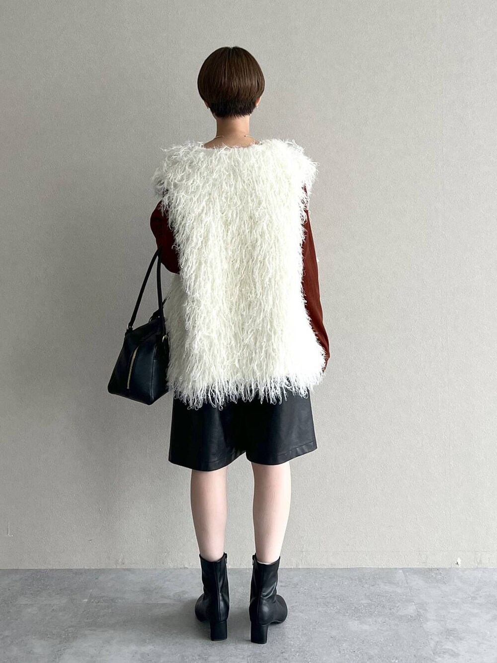 ブラック系のハンドバッグ、ホワイト系のベスト、ブラウン系のTシャツ/カットソーを着用したレディースの秋コーディネートの3枚目の写真