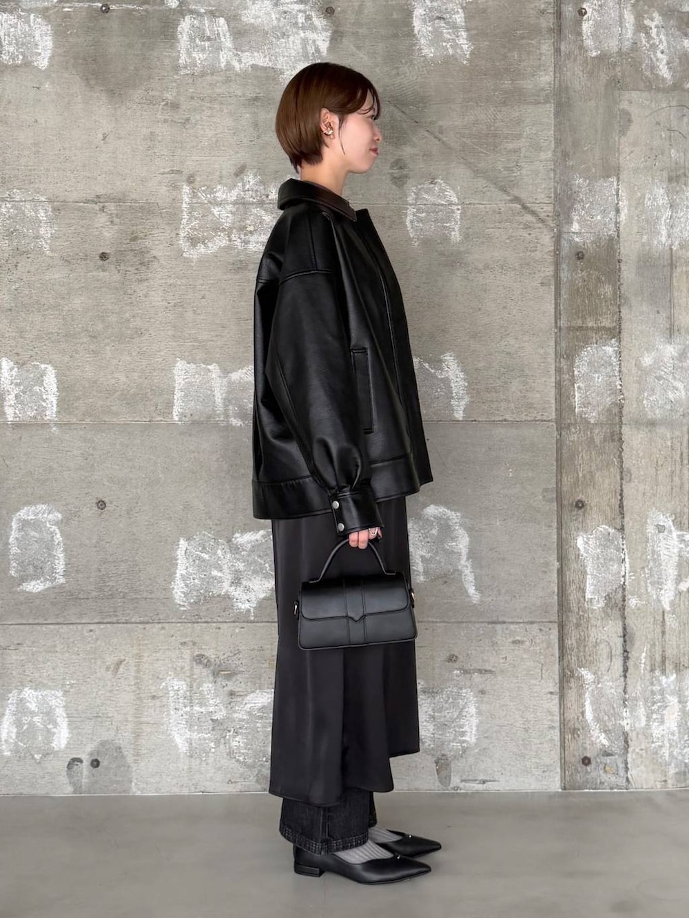 ブラック系のショルダーバッグ、ブラック系のデニムパンツ、ブラック系のパンプスを着用したレディースの冬コーディネートの3枚目の写真