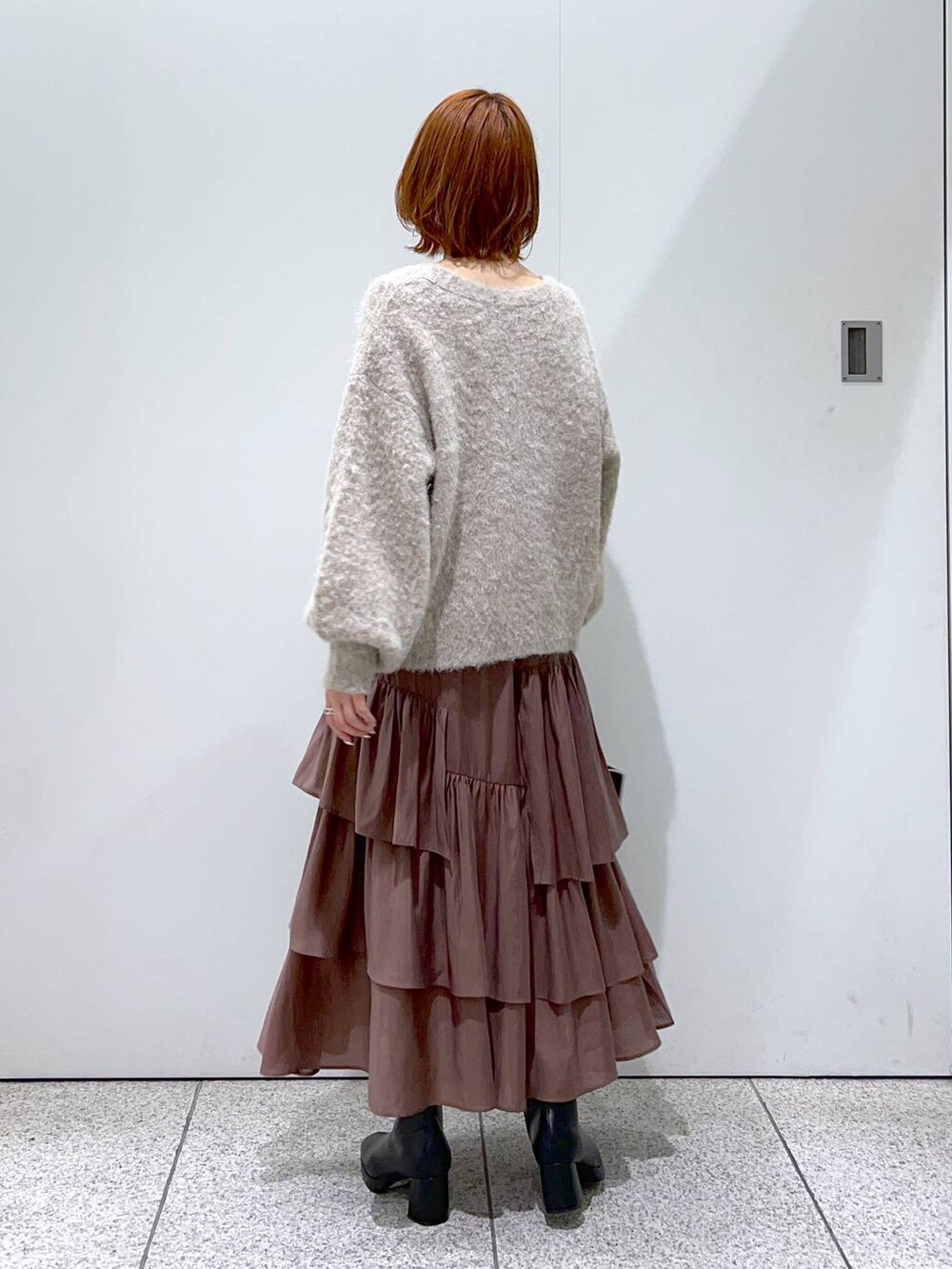 ブラック系のハンドバッグ、ブラック系のブーツ、ブラウン系のカーディガン/ボレロを着用したレディースの秋コーディネートの3枚目の写真