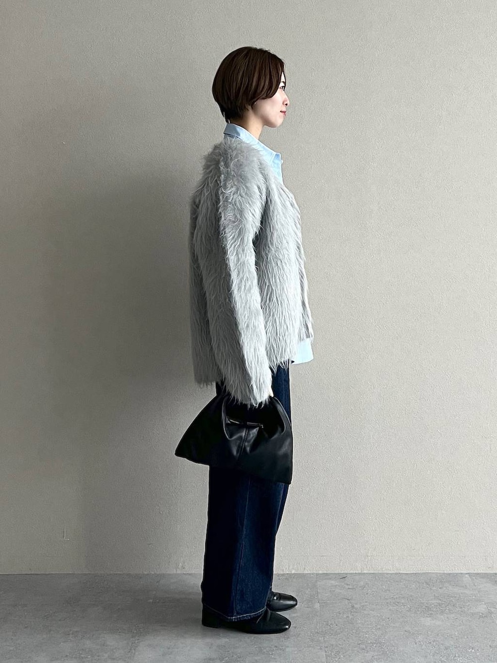 ブラック系のハンドバッグ、ブルー系のデニムパンツ、ブラック系のローファーを着用したレディースの秋コーディネートの2枚目の写真