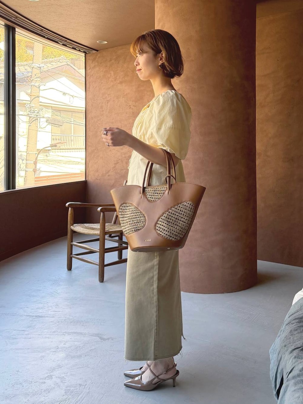 ブラウン系のトートバッグ、ブラウン系のサンダル、ホワイト系のシャツ/ブラウスを着用したレディースの春コーディネートの2枚目の写真